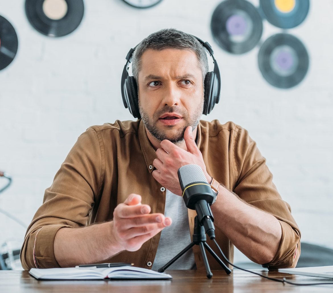 thoughtful-radio-host-in-headphones-recording-podcast-in-broadcasting-studio-e1664708812456.jpg